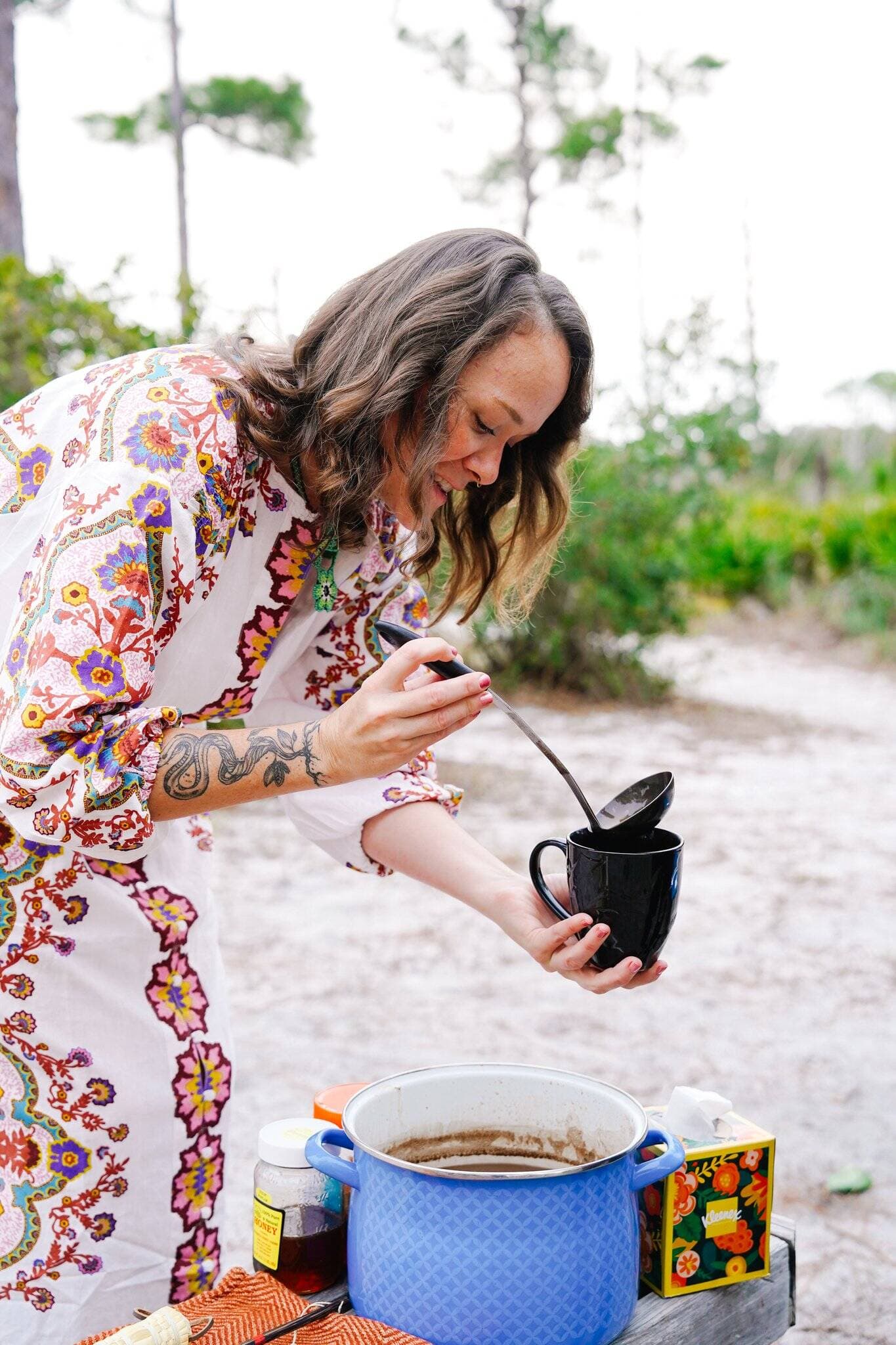 Kristina ladling freshly prepared ceremonial cacao into a cup outdoors
